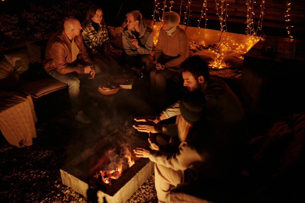 People chilling around fire in backyard at night